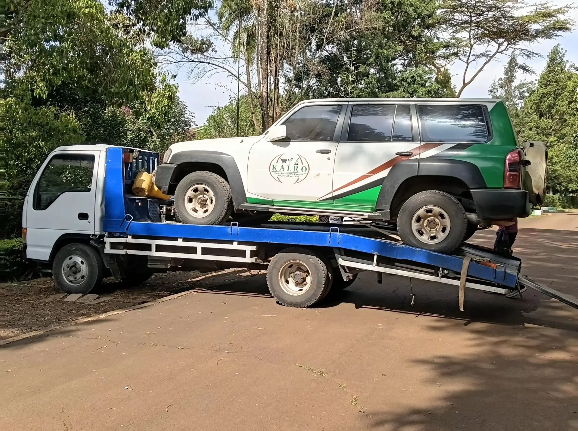 Flatbed tow truck transporting an SUV on a roadside